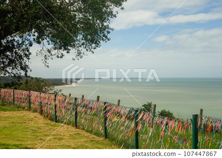 Porto Seguro, Bahia, Brazil: colorful souvenir ribbons hanging on the railing, sea on background 107447867