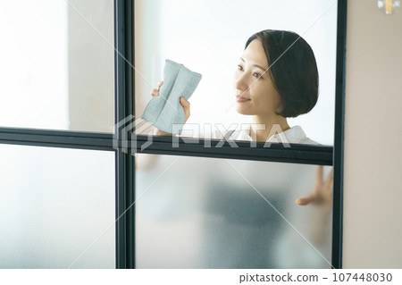 A woman in an apron cleaning windows A woman in an apron cleaning windows 107448030