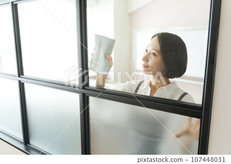 A woman in an apron cleaning windows A woman in an apron cleaning windows 107448031