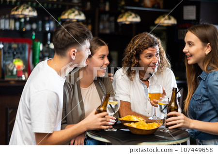 Spending time in bar. Four positive friends drinking beer 107449658
