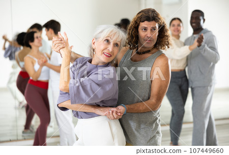 Caucasian man and mature woman learning paired latin dances 107449660