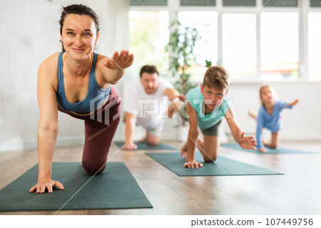 Confident mom, dad, son and daughter perform bird dog power asana Confident mom, dad, son and daughter perform bird dog power asana 107449756