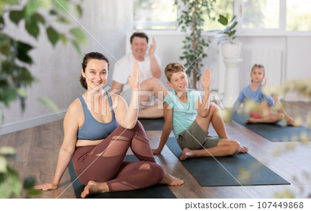 Family with two children doing yoga in studio 107449868