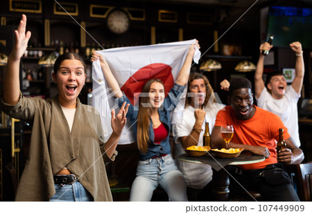 Young female fan happy with victory of favorite Japanese team in sports bar Young female fan happy with victory of favorite Japanese team in sports bar 107449909