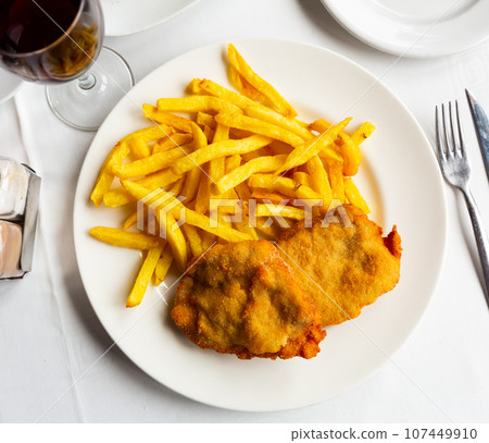 Deep-fried pork filet in crispy coating with side dish of french fries 107449910