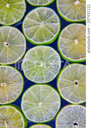 Bright and see through green lime slices on navy blue background 107452121