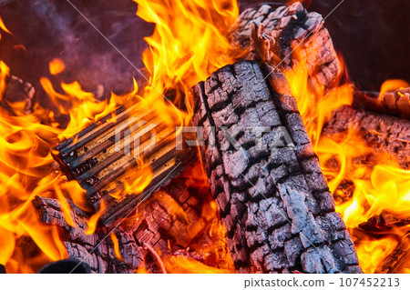 Close up of destroyed wooden logs in fire with large yellow and orange flames background asset 107452213