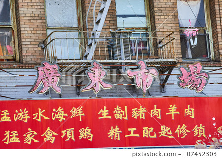Chinese sign below worn down fire escape with red banner in Chinatown Chinese sign below worn down fire escape with red banner in Chinatown 107452303
