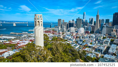 Aerial capturing the bay and Oakland Bay Bridge with Coit Tower close up and city skyscrapers 107452525