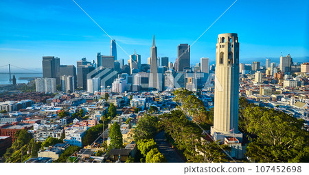 Aerial Coit Tower in late afternoon with downtown San Francisco skyscrapers and distant bridge Aerial Coit Tower in late afternoon with downtown San Francisco skyscrapers and distant bridge 107452698
