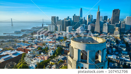 Aerial of roof of Coit Tower overlooking downtown skyscrapers and Oakland Bay Bridge Aerial of roof of Coit Tower overlooking downtown skyscrapers and Oakland Bay Bridge 107452706