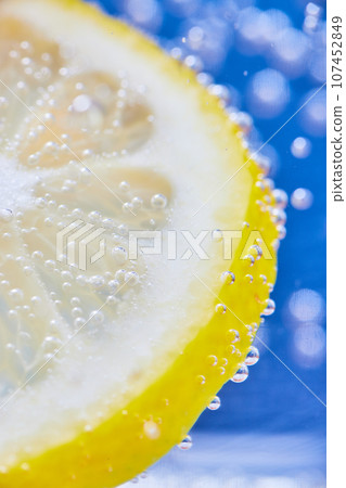 Yellow lemon slice with silvery bubbles and blue background Yellow lemon slice with silvery bubbles and blue background 107452849
