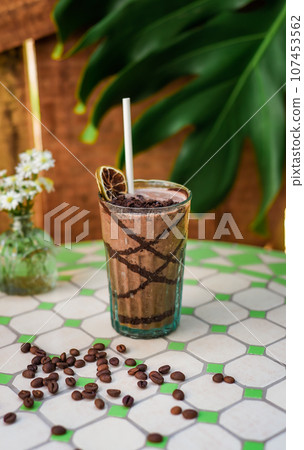 Cacao drink with banana and peanut butter on a table with vase of flowers Cacao drink with banana and peanut butter on a table with vase of flowers 107453562