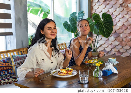 two beautiful women friends eating breakfast in cafe and talking two beautiful women friends eating breakfast in cafe and talking 107453628
