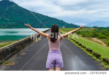 Young russian woman traveler with opened arms near lake and mountains in Khanh Hoa Province, Vietnam Young russian woman traveler with opened arms near lake and mountains in Khanh Hoa Province, Vietnam 107454484