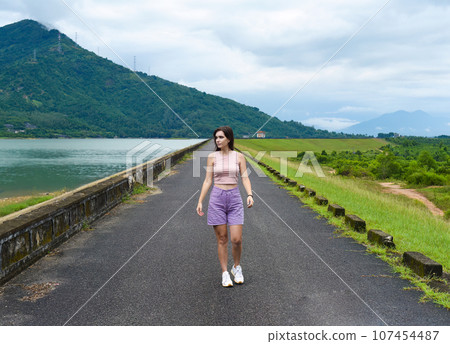 Young russian woman traveler with depressed and sad face walking alone near lake and mountains in Khanh Hoa Province, Vietnam 107454487
