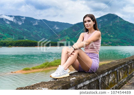 Young russian woman sitting with depressed and sad face against lake and mountains in Khanh Hoa Province, Vietnam 107454489