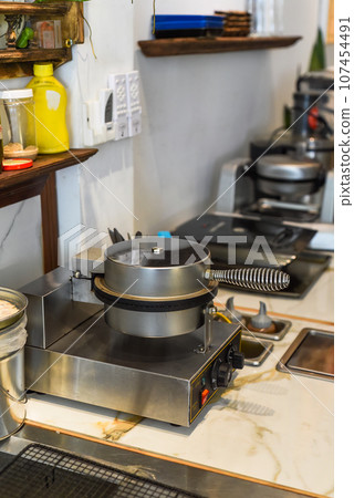 the cook puts the dough for sweet waffles into the waffle iron with a spoon the cook puts the dough for sweet waffles into the waffle iron with a spoon 107454491