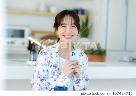 A young woman operating a smartphone 107454715
