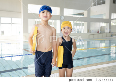 Brothers laughing while holding a beat board in an indoor pool 107455755