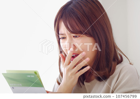 一個女人看著她的儲蓄存摺,表情悲傷 一個女人看著她的儲蓄存摺,表情悲傷 107456799