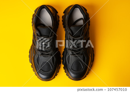 Black new sport sneakers on yellow background Black new sport sneakers on yellow background 107457010