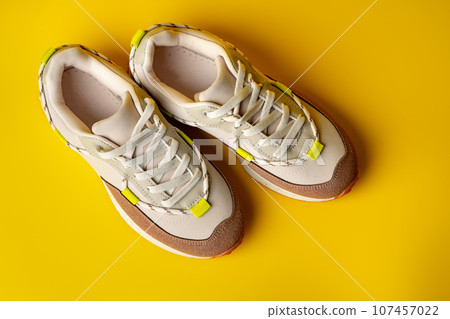 Beige sport running shoes on yellow studio background 107457022
