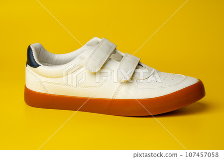 White leather sneakers with advehise fasteners on yellow background White leather sneakers with advehise fasteners on yellow background 107457058