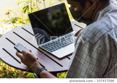 Happy Asian hand black man person working with laptop computer and reading message from modern smart phone blank screen device technology and connecting networking online at the coffee cafe shop Happy Asian hand black man person working with laptop computer and reading message from modern smart phone blank screen device technology and connecting networking online at the coffee cafe shop 107457096