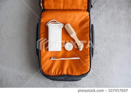 Plastic free travel, traveling sustainably. How to use less plastic on holiday. Eco Friendly Travel Products in orange suitcase. 107457697