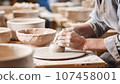 Potter working on pottery wheel in a pottery workshop. 107458001