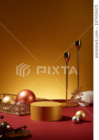Cylinder pedestal in golden color displayed with a tray of baubles and a reindeer. Blank space on the podium for product presentation. For Christmas photography 107458425
