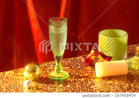 A glass filled with wine decorated with some Christmas ornaments on sparkling surface. Christians celebrate Christmas Day as the anniversary of the birth of Jesus of Nazareth A glass filled with wine decorated with some Christmas ornaments on sparkling surface. Christians celebrate Christmas Day as the anniversary of the birth of Jesus of Nazareth 107458454