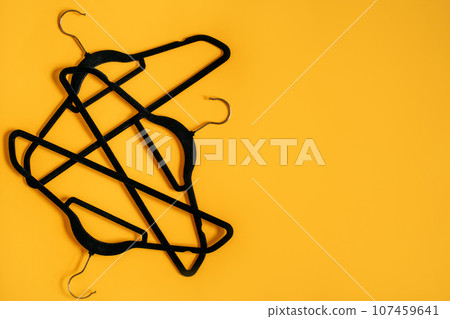 Black Friday Sale sustainable fashion concept with many black Clothes Hanger on yellow. Store, sale, save money, shopping planning concept, empty hanger. 107459641