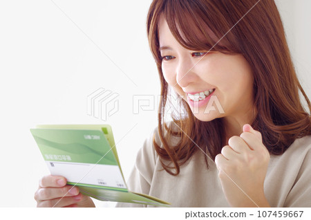一位年輕女子很高興地看著她的儲蓄存摺 107459667