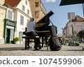 A girl plays the piano on the street of an old European city 107459906