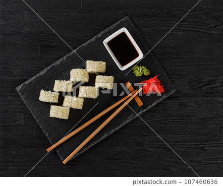 Sushi with salmon on a white plate with wasabi, ginger, soy, chopsticks on a black background Sushi with salmon on a white plate with wasabi, ginger, soy, chopsticks on a black background 107460636