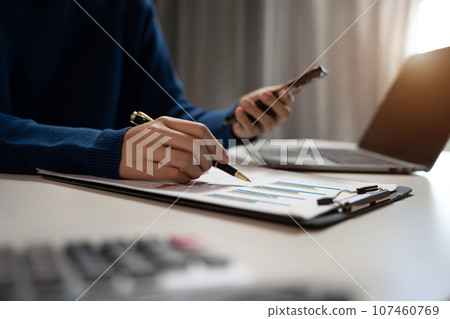 Businessman working on calculator to calculate financial data report, accountancy document and laptop computer at office, business concept. Businessman working on calculator to calculate financial data report, accountancy document and laptop computer at office, business concept. 107460769