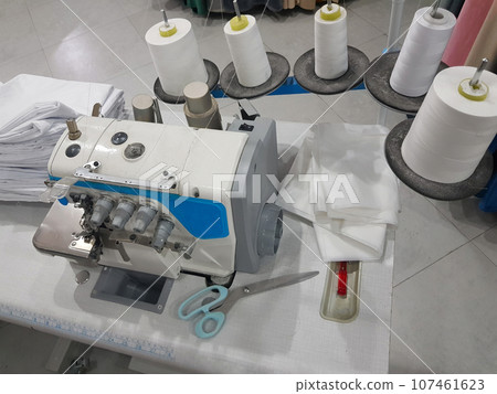 Tailor workshop with white sewing thread and sewing machine, details and fabric Tailor workshop with white sewing thread and sewing machine, details and fabric 107461623