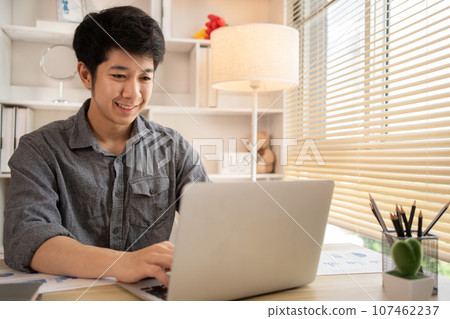 Man sat typing away on a laptop in his office with a determined look on his face, Work from the comfort of home, Male hand pressing on laptop keyboard, Work from home. Man sat typing away on a laptop in his office with a determined look on his face, Work from the comfort of home, Male hand pressing on laptop keyboard, Work from home. 107462237