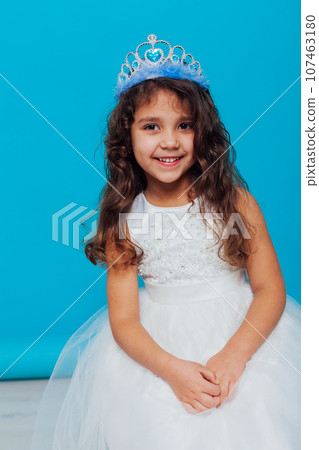 a girl in a white dress with a crown on her head for a holiday on a blue background a girl in a white dress with a crown on her head for a holiday on a blue background 107463180