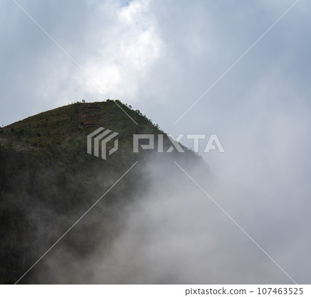 Unrecognizable People at Foggy Mountain Peak Under Cloudy Sky 107463525