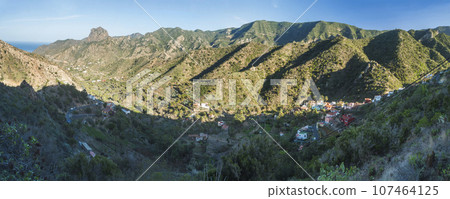 Panoramic view of village Arure in green valley with palm trees and traditional colorful houses. Valle Gran Rey, La Gomera, Canary Islands, Spain, Europe. Blue sky white clouds background 107464125