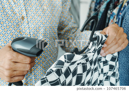 shop assistant scanning a barcode in a clothes shop using 107465706