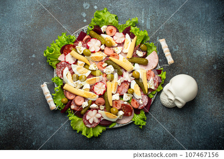Close up of Fiambre, salad of Guatemala, Mexico and Latin America top view with ceremonial symbolical skull. Festive dish for All Saints Day (Day Of The Dead) celebration 107467156