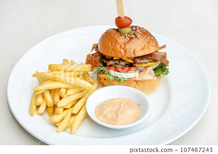 Single cheeseburger with bacon and French fries on table Single cheeseburger with bacon and French fries on table 107467243
