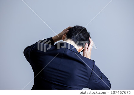 Rear view of a man holding his head Rear view of a man holding his head 107467675