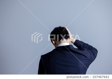 Rear view of a man holding his head 107467681