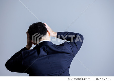 Rear view of a man holding his head 107467689