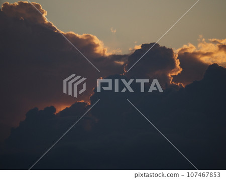 Silhouettes of cumulonimbus clouds illuminated by the summer sunset Silhouettes of cumulonimbus clouds illuminated by the summer sunset 107467853
